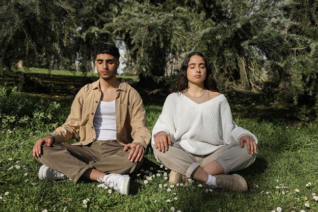 Man and woman sitting in grass meditating.
